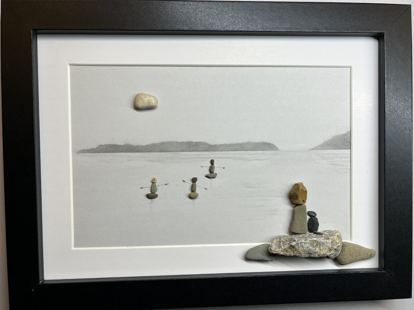 pebble art, lady and dog sitting at the lake watching 3 kayakers